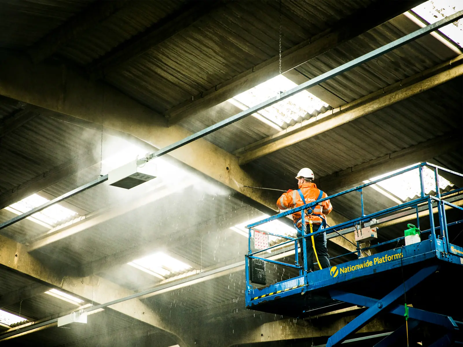 Nhân viên vệ sinh trần nhà xưởng trên xe nâng người